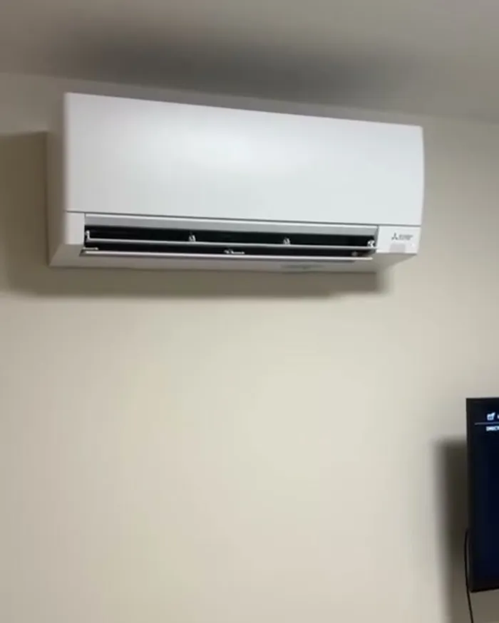 Split Mitsubishi Electric instalado sobre un panel de madera en un dormitorio