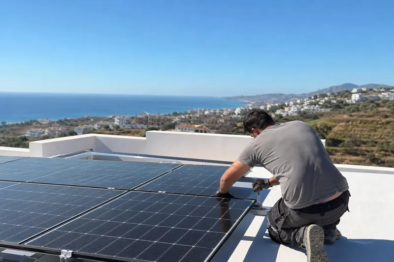 Placas solares instaladas en la azotea de una casa con el mar al fondo